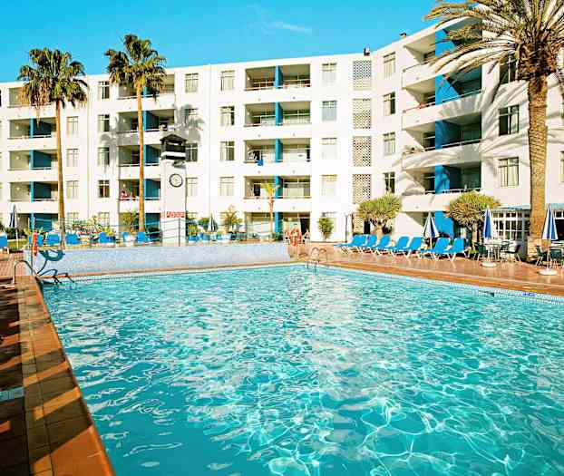 Uima-allas hotellin yhteydessä, jossa on aurinkotuoleja, varjoja ja palmuja taustalla. (Tekoälyn luoma teksti)