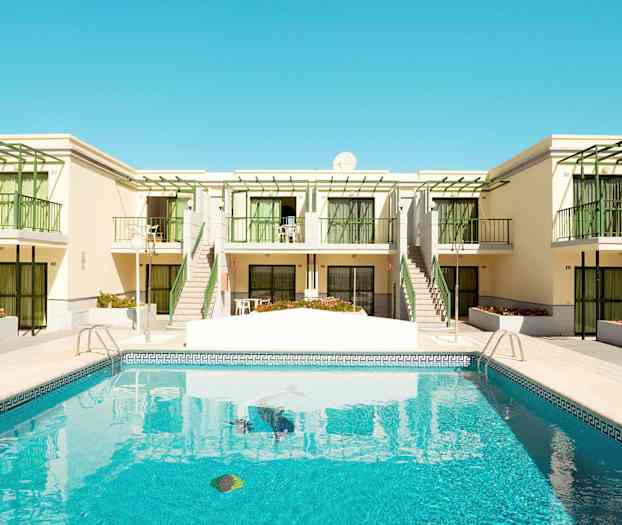 Uima-allas rakennuksen edessä, jossa on parvekkeita ja vihreitä yksityiskohtia. (Tekoälyn luoma teksti)