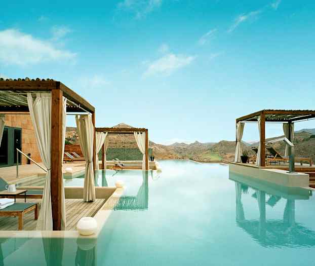 Infinity-allas, josta on näkymä vuoristomaisemiin, ympäröivät terassit aurinkotuoleilla katosten alla. (Tekoälyn luoma teksti)