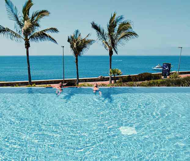 Infinity-allas meren rannalla, taustalla palmuja. (Tekoälyn luoma teksti)