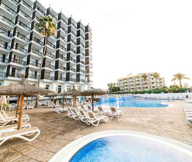 Kuva hotellialueesta, jossa uima-allas, aurinkotuoleja ja varjokatos. (Tekoälyn luoma teksti)