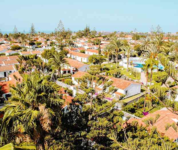 Näkymä lomakohteesta, jossa valkoisia taloja, punaisia kattoja ja vihreitä puita ympärillä. (Tekoälyn luoma teksti)