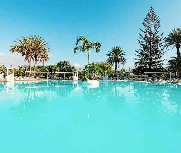 Suuri turkoosi uima-allas, jonka ympärillä on aurinkotuoleja ja palmuja. (Tekoälyn luoma teksti)