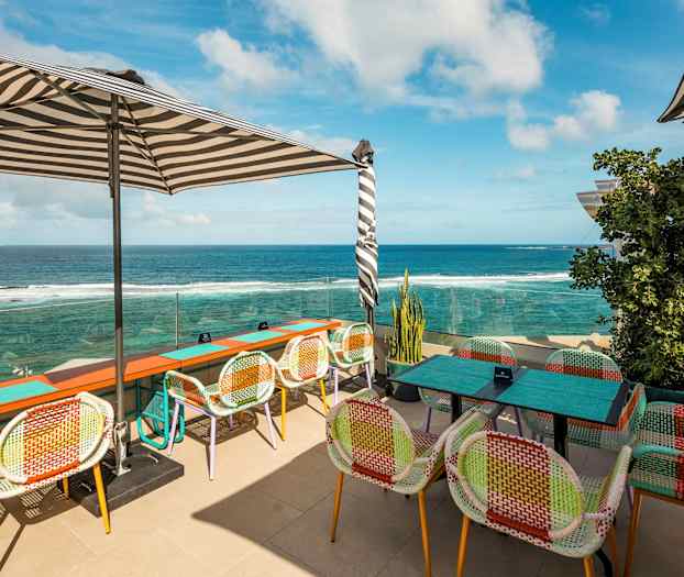 Ulkoterassi, jossa värikkäitä tuoleja ja näkymät merelle. (Tekoälyn luoma teksti)