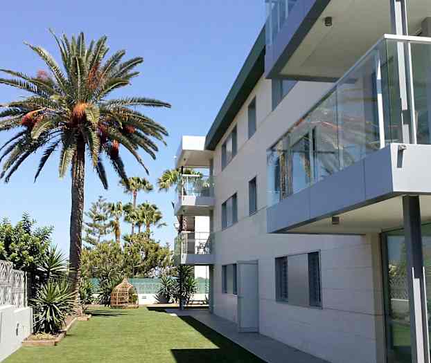 Nykyaikainen rakennus ruohokentän vieressä, jossa on palmuja. (Tekoälyn luoma teksti)