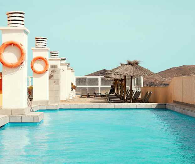 Ulkouima-allas, jonka vieressä on aurinkotuoleja ja varjoja. (Tekoälyn luoma teksti)