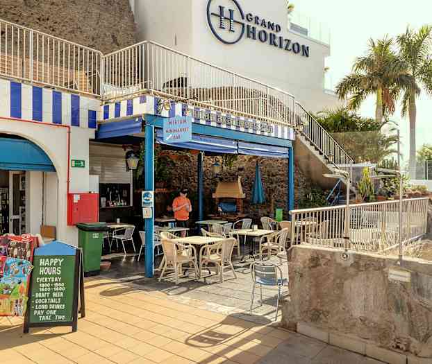 Kuva kaupastata ja kahvilasta, joissa on ulkona pöytiä ja tuoleja. (Tekoälyn luoma teksti)