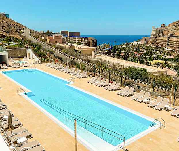 Ulkouima-allas, jota ympäröivät aurinkotuolit, taustalla merinäkymä. (Tekoälyn luoma teksti)