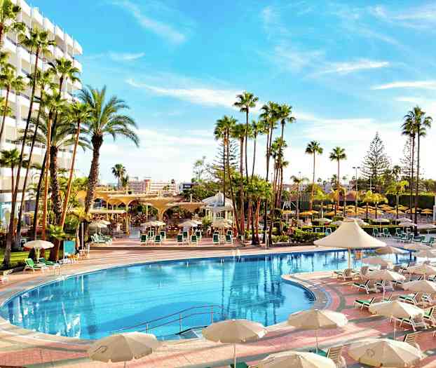 Suuri ulkouima-allas hotellin vieressä, ympärillä aurinkotuoleja ja varjoja. (Tekoälyn luoma teksti)