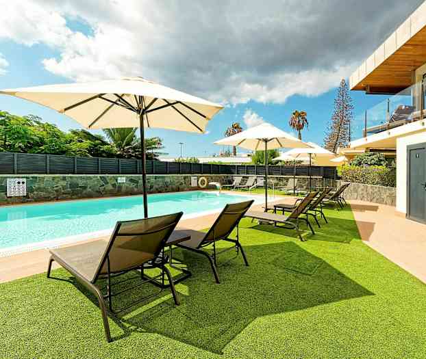 Ulkouima-allas, jossa aurinkotuoleja ja -varjoja nurmikolla ja terassilla. (Tekoälyn luoma teksti)