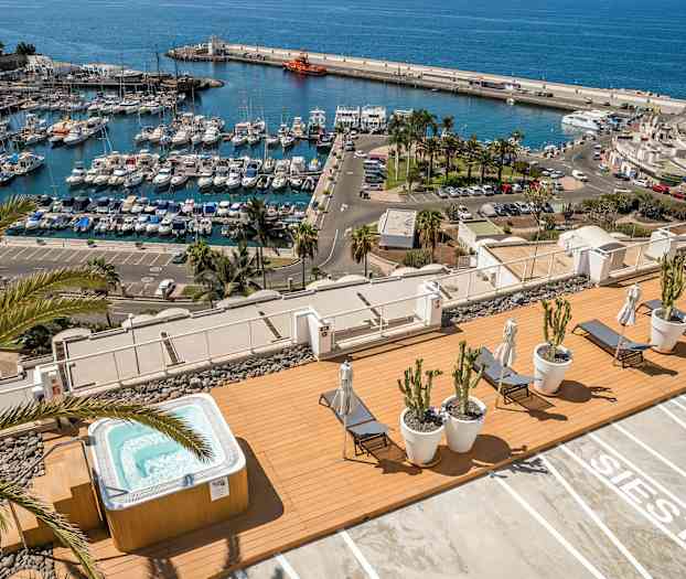 Näkymä satamaan veneineen sekä terassi porealtaan ja aurinkotuolien kanssa. (Tekoälyn luoma teksti)