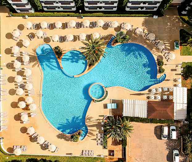 Ilmakuva uima-altaasta, jonka ympärillä on aurinkotuoleja ja -varjoja. (Tekoälyn luoma teksti)