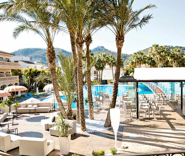 Uima-allasalue aurinkotuoleineen, päivänvarjoineen, palmuineen ja rakennuksineen taustalla. (Tekoälyn luoma teksti)