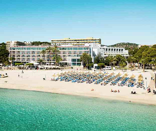 Ranta, jossa on aurinkovarjoja ja aurinkotuoleja, suuren parvekkeellisen rakennuksen edessä. (Tekoälyn luoma teksti)