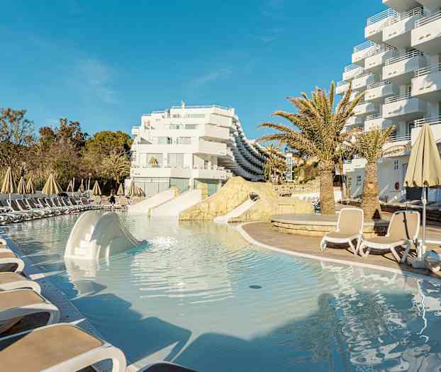 Uima-allasalue, jossa aurinkotuoleja ja varjoja hotellin yhteydessä. (Tekoälyn luoma teksti)