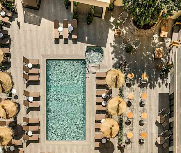 Lintuperspektiivi uima-altaasta, jota ympäröivät aurinkotuolit, aurinkovarjot ja pöydät. (Tekoälyn luoma teksti)