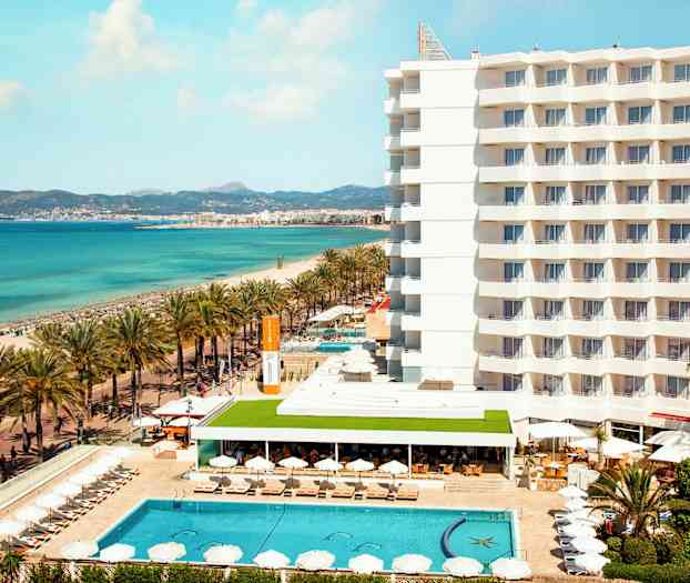 Hotelli rannalla, jossa uima-allas ja aurinkotuoleja, taustalla meri. (Tekoälyn luoma teksti)