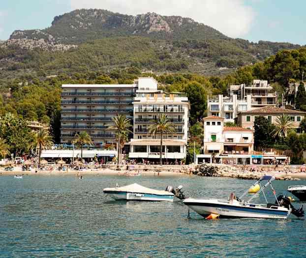 Kuva rannikkokaupungista, jossa on hotelli, ranta ja veneitä vedessä. (Tekoälyn luoma teksti)