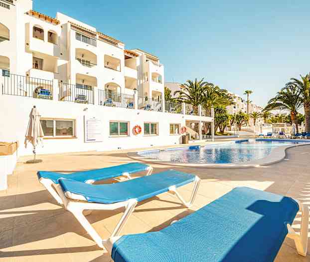 Ulkouima-allas, jossa aurinkotuoleja, ja taustalla valkoisia rakennuksia. (Tekoälyn luoma teksti)