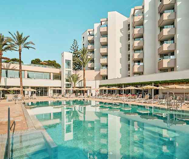 Hotelli, jonka parvekkeet ympäröivät uima-allasta, jossa on aurinkotuoleja ja varjoja. (Tekoälyn luoma teksti)