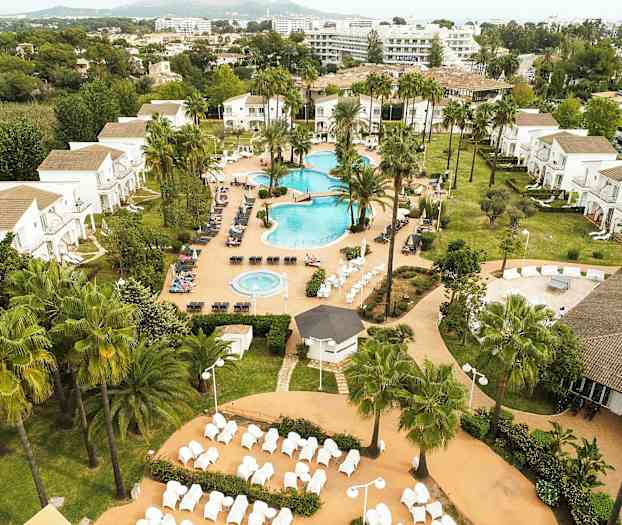 Lomahotelli, jossa on uima-allasalue, viheralueita ja rakennuksia taustalla. (Tekoälyn luoma teksti)