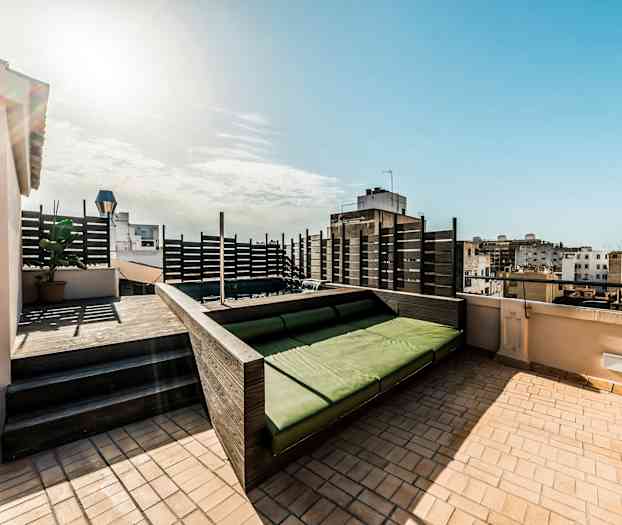 Kattoterassi, jossa on vihreä istuinalue ja näkymä ympäröiviin rakennuksiin. (Tekoälyn luoma teksti)