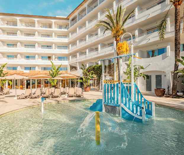 Ulkona oleva allasalue, jossa lasten leikkipaikka ja aurinkotuoleja hotellirakennuksen edessä. (Tekoälyn luoma teksti)