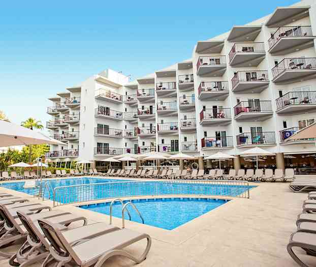 Useita aurinkotuoleja ja varjoja ulkouima-altaan äärellä monikerroksisen rakennuksen edessä. (Tekoälyn luoma teksti)