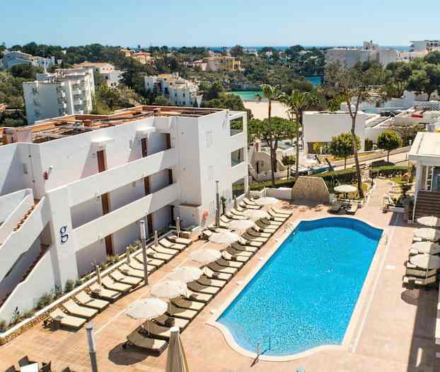 Kuva hotellialueesta, jossa on uima-allas ja aurinkotuoleja. Taustalla näkyy viheralueita ja rakennuksia. (Tekoälyn luoma teksti)