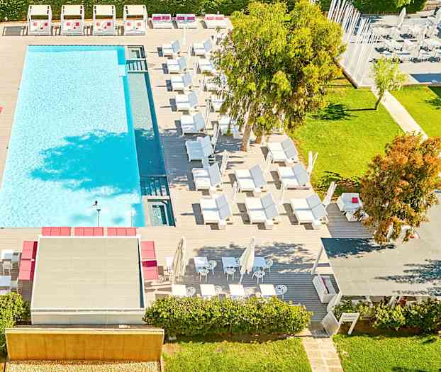 Näkymä ylhäältä ulkouima-altaalle, jota ympäröivät aurinkotuolit ja viheralueet. (Tekoälyn luoma teksti)