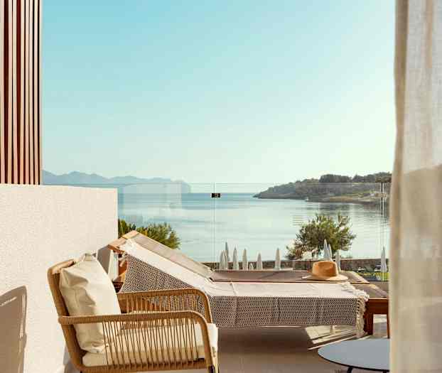 Näkymä terassilta, jossa on aurinkotuoli ja lasikaide, taustalla näkyy meri ja maisema. (Tekoälyn luoma teksti)