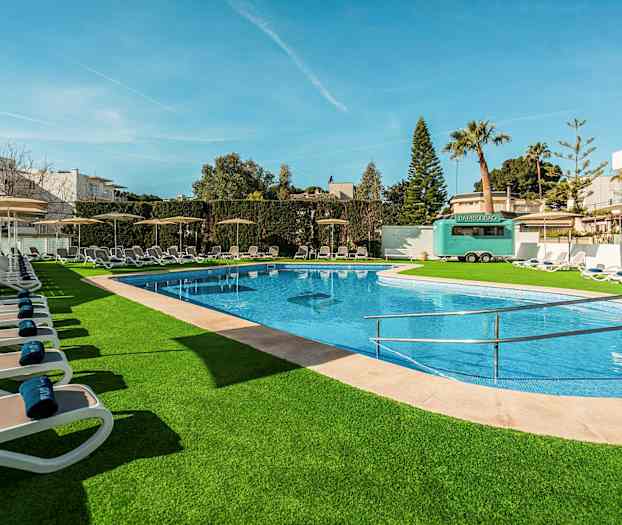 Uima-allas ulkona, jossa aurinkotuoleja ja vihreitä ympäristöjä. (Tekoälyn luoma teksti)