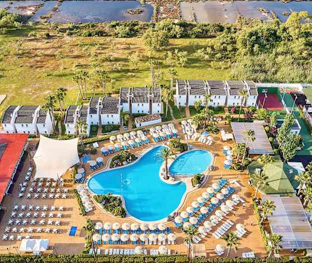 Ilmakuva hotellialueesta, jossa on uima-altaita, aurinkotuoleja ja valkoisiksi maalattuja rakennuksia vehreyden ympäröimänä. (Tekoälyn luoma teksti)
