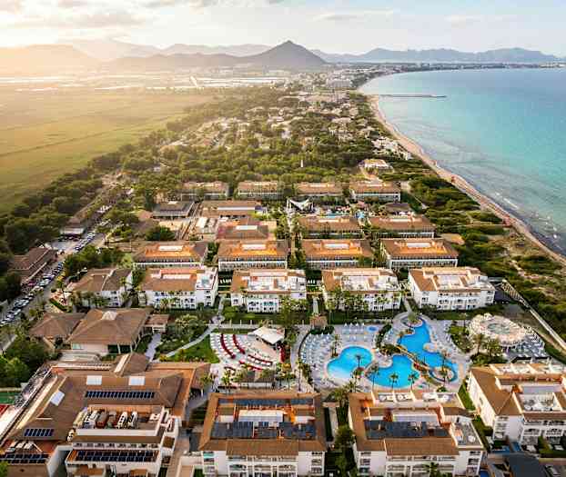 Ilmakuva lomakeskuksesta, jossa on hotelleja ja uima-allas rannalla. (Tekoälyn luoma teksti)