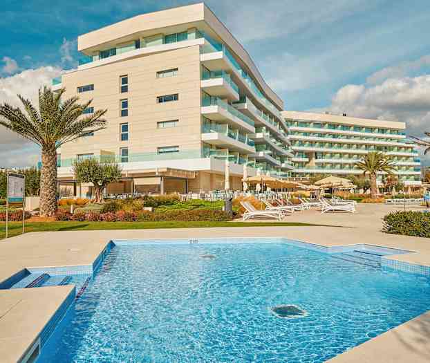 Kuva hotellista, jossa on nykyaikaisia rakennuksia, uima-allas ja ulkoloungealueita. (Tekoälyn luoma teksti)