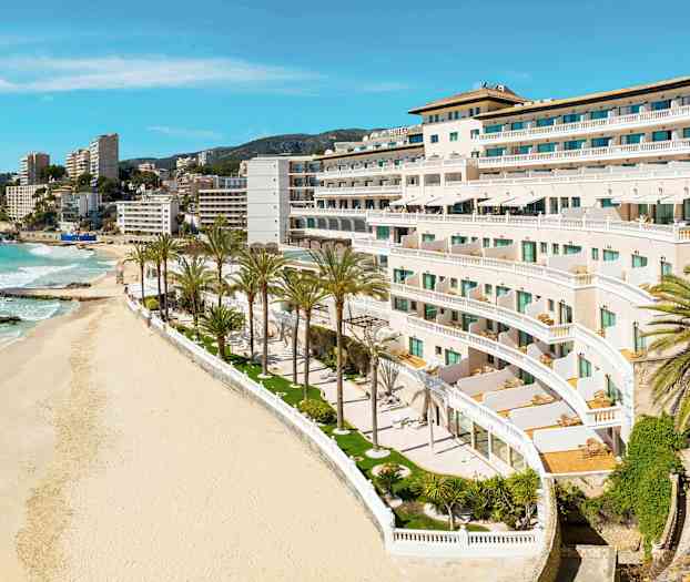 Kuva rannasta, jossa palmuja ja valkoisia rakennuksia lomakohteessa. (Tekoälyn luoma teksti)