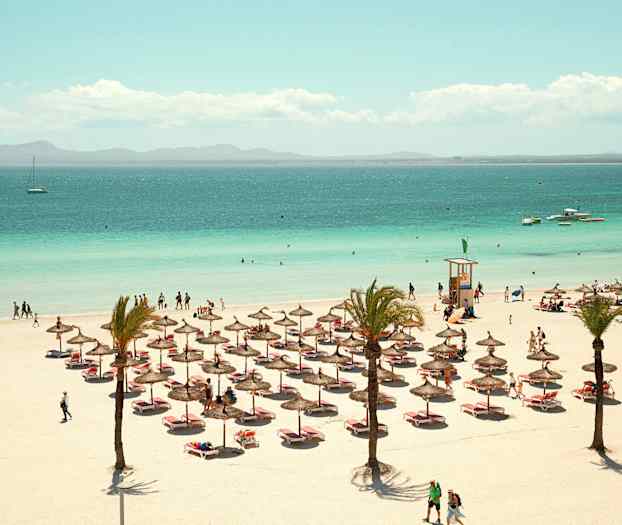 Ranta aurinkovarjoineen, aurinkotuoleineen ja ihmisineen; taustalla meri. (Tekoälyn luoma teksti)