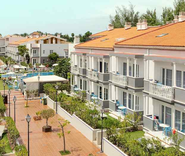 Hotellikompleksi, jossa on useita rakennuksia, uima-allasalue ja puutarha. (Tekoälyn luoma teksti)