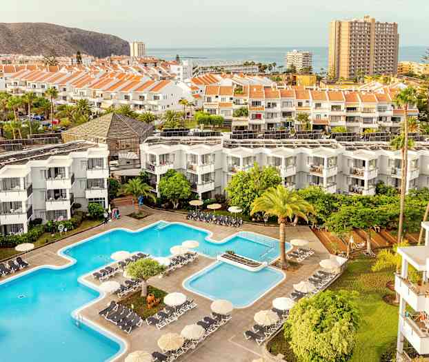 Näkymä hotellialueelle, jossa uima-altaita, rakennuksia ja ympäröivää maisemaa. (Tekoälyn luoma teksti)