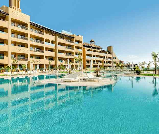 Hotellin ulkouima-allas aurinkotuoleilla ja ympäröivillä rakennuksilla. (Tekoälyn luoma teksti)