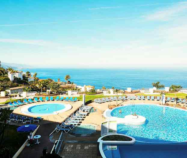 Kuva hotellista, jossa etualalla on uima-allasalue ja taustalla merinäkymä. (Tekoälyn luoma teksti)