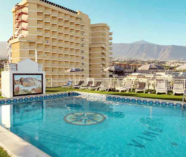 Hotellin uima-allas, aurinkotuoleja ja näkymä vuorille ja rakennuksille. (Tekoälyn luoma teksti)