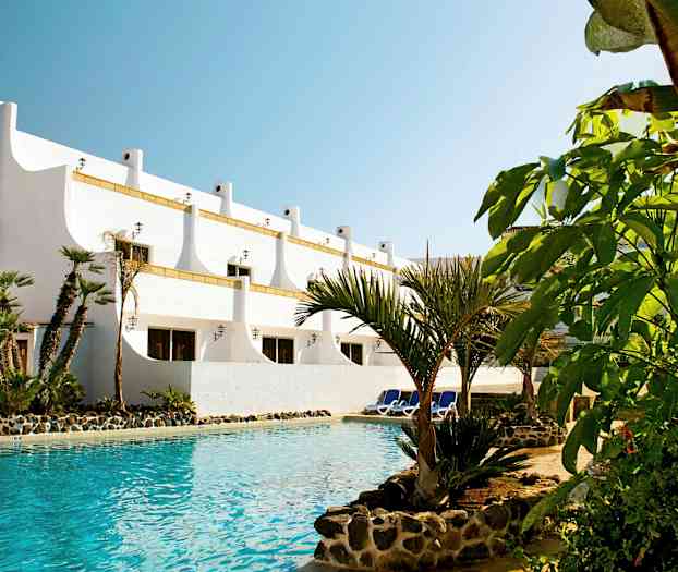 Valkoinen rakennus, palmuja uima-altaan äärellä. (Tekoälyn luoma teksti)