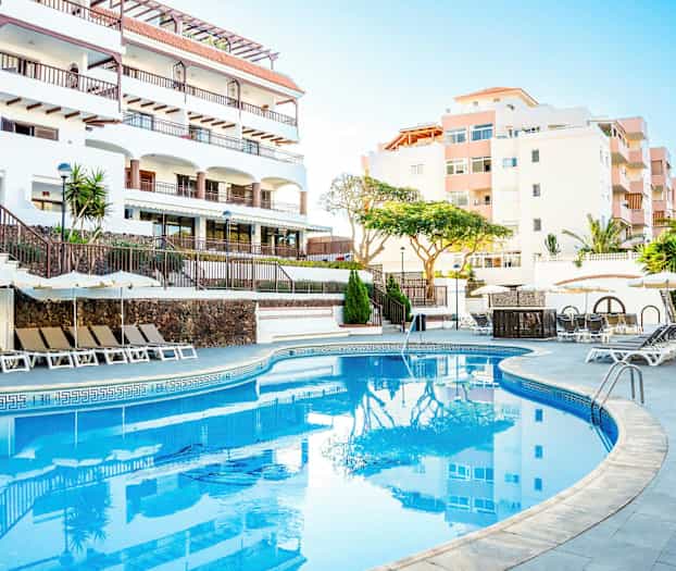 Ulkoallas, jossa on aurinkotuoleja ja aurinkovarjoja hotellin luona. (Tekoälyn luoma teksti)