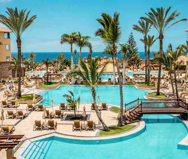 Hotellin uima-allasalue aurinkotuoleilla, palmuilla ja merinäkymällä. (Tekoälyn luoma teksti)