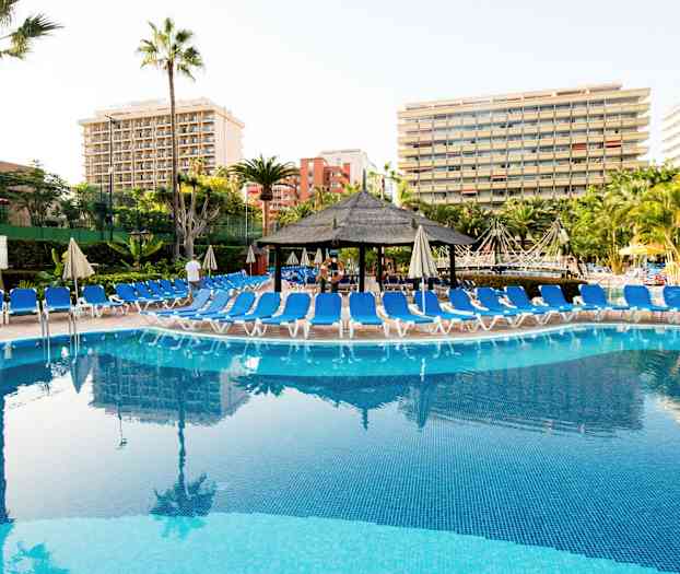 Uima-allas, jonka ympärillä on aurinkotuoleja ja hotellirakennuksia taustalla. (Tekoälyn luoma teksti)