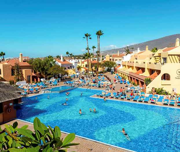 Iso ulkouima-allas, jota ympäröivät aurinkotuolit ja rakennukset, taustalla vuoria. (Tekoälyn luoma teksti)