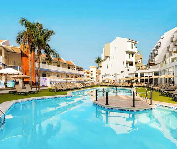 Mukava uima-allasalue hotellissa, jossa aurinkotuoleja, varjoja ja ympäröiviä rakennuksia. (Tekoälyn luoma teksti)