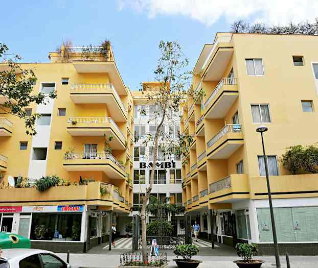 Keltainen rakennus parvekkeilla ja liikkeitä pohjakerroksessa. (Tekoälyn luoma teksti)