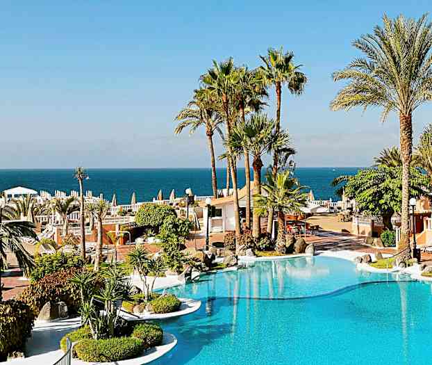 Lomakohde, jossa on uima-allas, palmuja ympärillä ja näkymä merelle taustalla. (Tekoälyn luoma teksti)